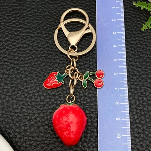 Detail view of resin strawberry keychain with measurements against a black leather background