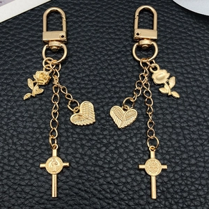 Porte-clés doré avec rose, cœur ailé et croix de Saint-Benoît sur cuir noir