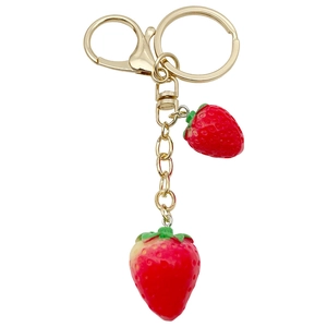 Realistic red resin strawberry keychain with green leaves and golden metal hardware on white background