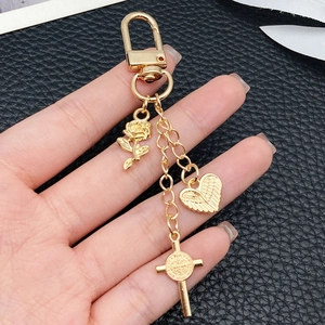 Porte-clés doré avec rose, cœur ailé et breloques de croix sur fond en cuir noir