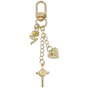 Porte-clés doré avec rose, cœur ailé et pendentif croix avec médaille sur fond blanc