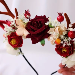 Detailansicht eines Weihnachts-Haarreif mit roten Rosen, braunem Geweih und Beeren