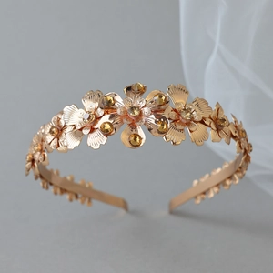 Exquisite gold flower headband crown with amber rhinestones on a neutral grey background