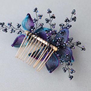Macro detail of handmade floral hair comb with purple petals and iridescent beaded branches