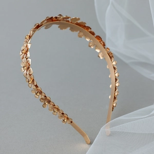 Close-up of golden metal flower headband with champagne rhinestones and petal texture