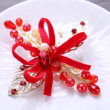 Close-up of handmade red velvet bow bridal hair clip with pearls and gold leaf detail