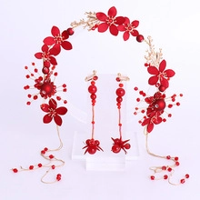 Detailed shot of handmade red bridal headpiece set with beaded flowers and tassel earrings
