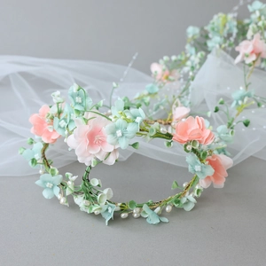 Détail d'un bandeau floral bohème avec pétales de soie roses, perles et tissage