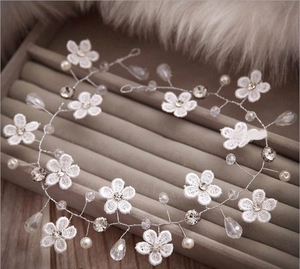 Détail d'un bandeau de mariée fait main avec fleurs en dentelle et perles sur écrin gris
