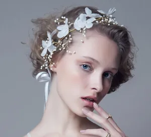 Detailed close-up of handmade white fabric flower hairpiece with pearls and gold wire