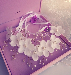Detail of bridal floral hairpiece with silk flowers, white pearls and long ribbons
