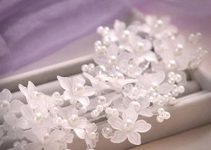 Detailansicht handgefertigter Brauthaarschmuck mit matten weißen Blüten und Perlen