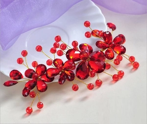 Close-up of handmade red crystal bridal hair comb with gold wire and beaded flowers