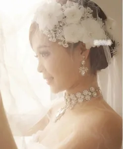 Detail of bridal lace floral headpiece set with pearls and crystal drop earrings