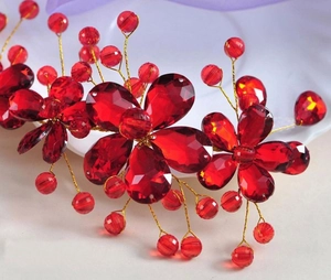 Macro detail of bridal hair accessory with red faceted crystal flowers and gold wire