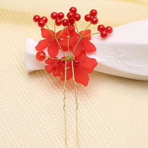 Close-up of red floral bridal hair pin with golden U-shaped clip and bead details