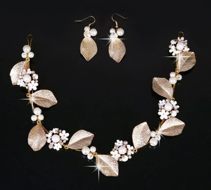 Detail von goldenem Braut-Haarschmuck und Ohrringen mit weißen Perlen und Strasssteinen
