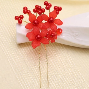 Detailed close-up of bridal hair pin with red resin flowers and faux pearls on gold stems