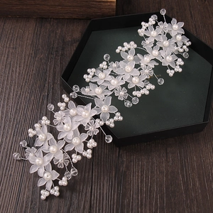 Eleganter Braut-Haarschmuck mit matten Blüten, weißen Perlen und Kristallen auf Holzgrund
