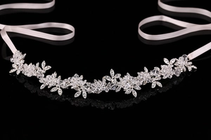 Close-up of bridal crystal headband with floral rhinestone patterns and white satin ribbon