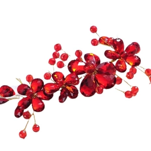 Handmade bridal hair accessory with red crystal flowers and gold wire on white background