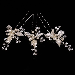Detail of three bridal hair pins with white alloy leaves, pearls, and crystals on black mirror