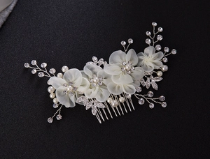 Détail macro du peigne de mariée avec fleurs en tissu crème, perles et strass brillants