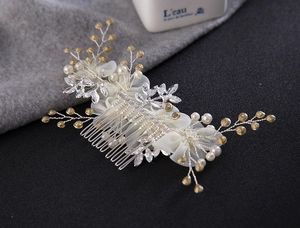 Vue détaillée d'un peigne de mariée avec feuilles argentées, perles et pétales blancs