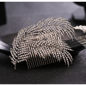 Macro shot of silver bridal hair comb with intricate leaf patterns and clear rhinestones