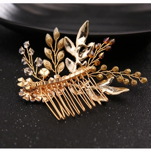 Detail of a handmade golden bridal hair comb with crystal beads and metal leaves
