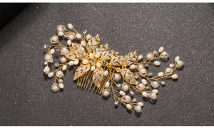 Close-up of golden leaf bridal hair comb with pearls and rhinestones on black background