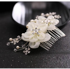 Macro view of white fabric bridal hair comb with star rhinestones and pearl details