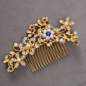 Close-up of golden bridal hair comb with pearls, clear rhinestones and blue crystals