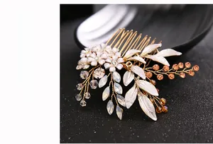 Detail of handcrafted bridal hair comb with gold leaves and white enamel floral accents