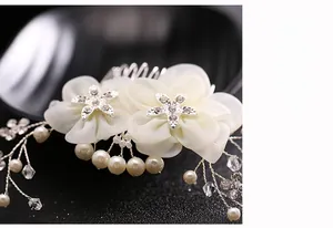 Macro detail of bridal hair comb with chiffon flowers, crystals, and faux pearls