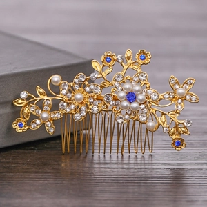Detailed shot of bridal hair comb with gold floral patterns, pearls and blue crystals