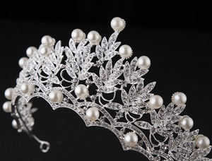 Detail of silver bridal crown featuring sparkling rhinestones and white pearls on black