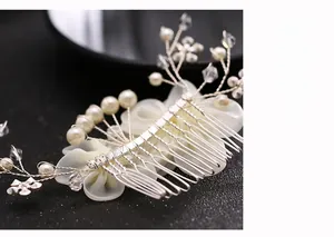 Close-up of bridal flower hair comb with white pearls, crystals and ivory fabric petals