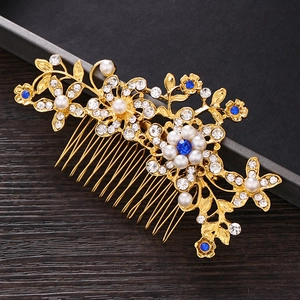 Detail of bridal hair comb with blue rhinestones, white pearls, and gold floral patterns