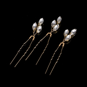 Detailed view of three gold bridal hair pins with leaf-shaped marquise crystals