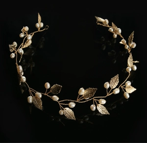Detail of bridal headband with gold metal leaves and delicate pearls on black background