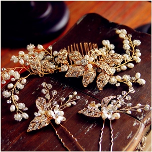 Close-up of golden leaf bridal hair comb set with white pearls and sparkling rhinestones