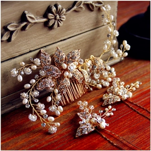 Macro detail of bridal hair comb and pins set with golden leaves and white pearls