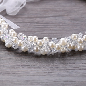 Handmade bridal headband with white pearls and crystals on dark wood background