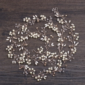 Dettaglio di un tralcio per capelli da sposa con perle bianche e cristalli dorati