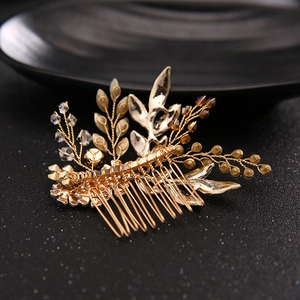 Elegant gold bridal hair comb with metallic leaves and beads on a dark background