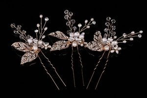 Detailed macro of golden metal leaf hair pins with sparkling crystals and pearls