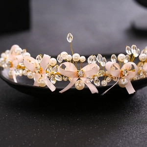 Handmade bridal headband with pink bows, white pearls, and crystals on a gold wire frame