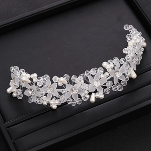 Detailed view of handmade crystal bridal headband with white flowers and pearls on black box