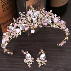 Detalle de una corona de novia con cristales rosas y pendientes a juego sobre madera